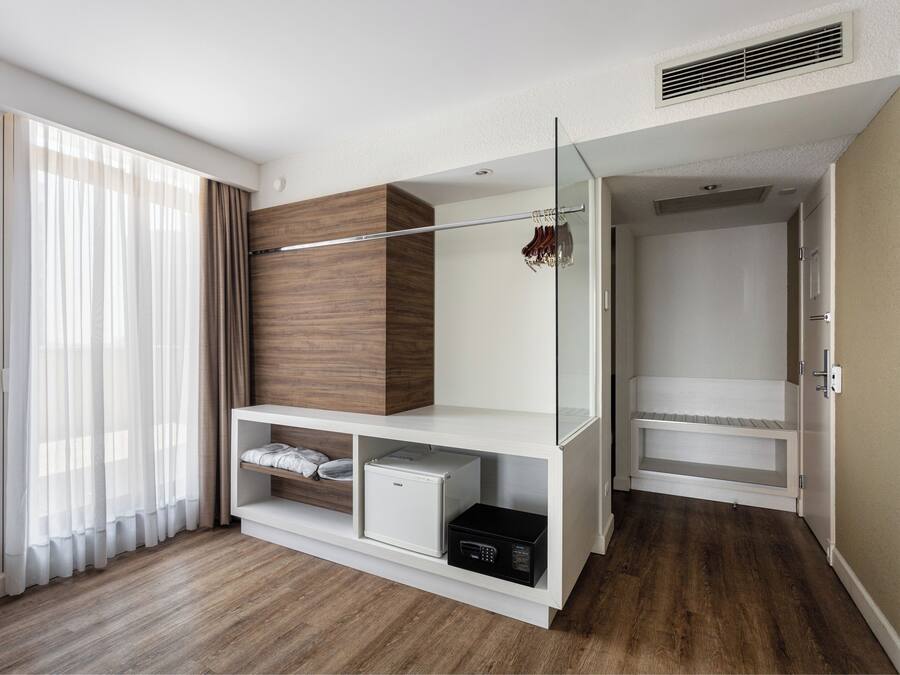 Una habitación de hotel moderna con armario empotrado, un refrigerador compacto y zona de ducha.