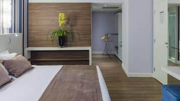 A modern hotel room with a bed, a bedside table, a potted plant, and a view of the hallway.