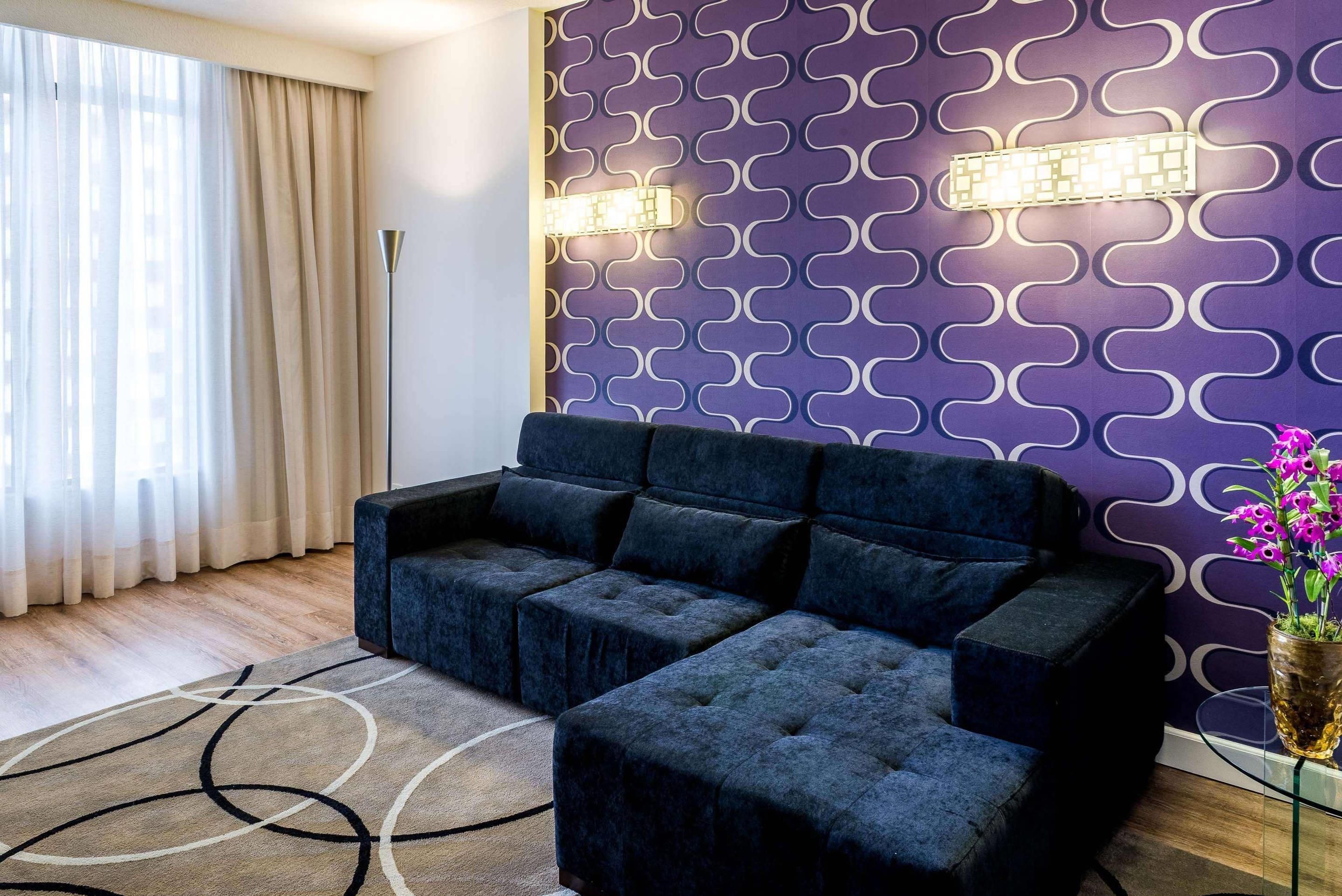 Una sala moderna con un sofá seccional, un muro estampado y una lámpara de pie.