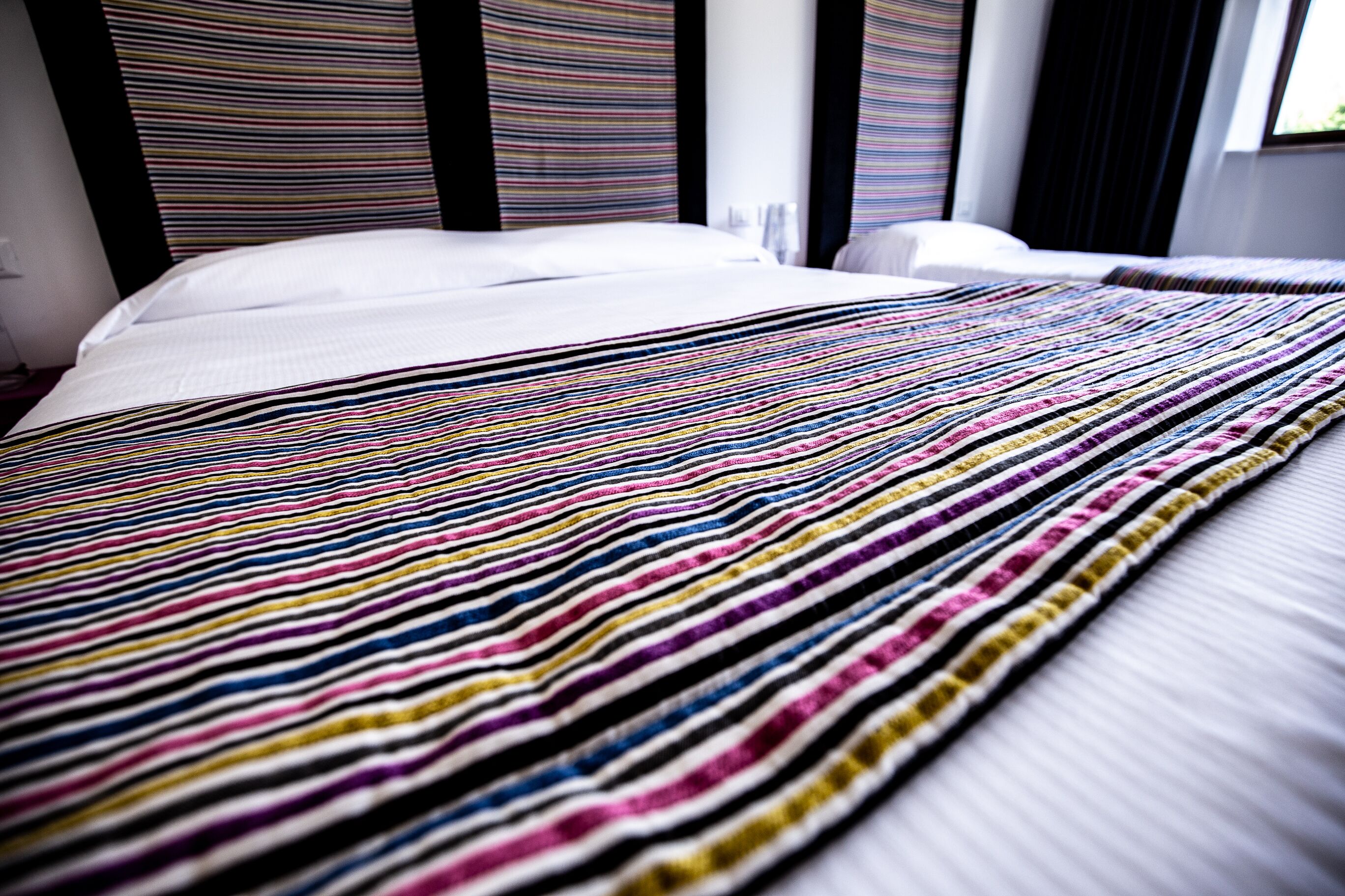 A bed with a striped blanket and a white pillow.