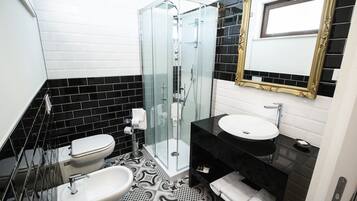 A bathroom with a glass-enclosed shower, two sinks, and a mirror with a gold frame.