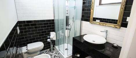 Un baño con ducha de vidrio, dos lavamanos y un espejo con marco dorado.