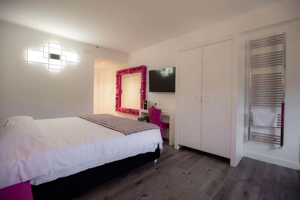 Ein Schlafzimmer mit Bett, Schreibtisch, Fernseher und Handtuchhalter.