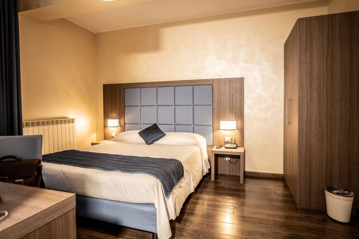 Ein Hotelzimmer mit Bett, Nachttischen, Schreibtisch, Stuhl und Kleiderschrank.
