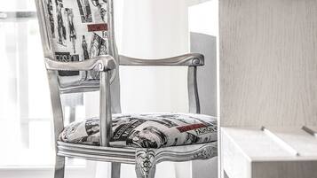 Una silla con tela estampada y una cafetera sobre una mesa.