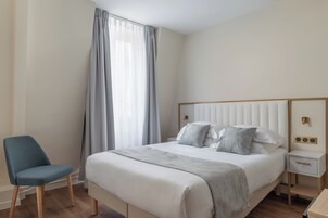 A neatly arranged bedroom with a bed, bedside table, and chair.