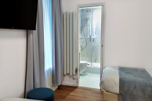 Un bagno moderno con doccia, WC e una porta in vetro che dà su un balcone.