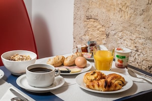 En frukostuppläggning med croissanter, ägg, juice och kaffe på ett bord.
