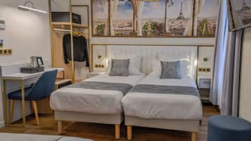 Une chambre d’hôtel avec deux lits, un bureau, une chaise, une armoire et une grande fresque murale représentant un paysage urbain.
