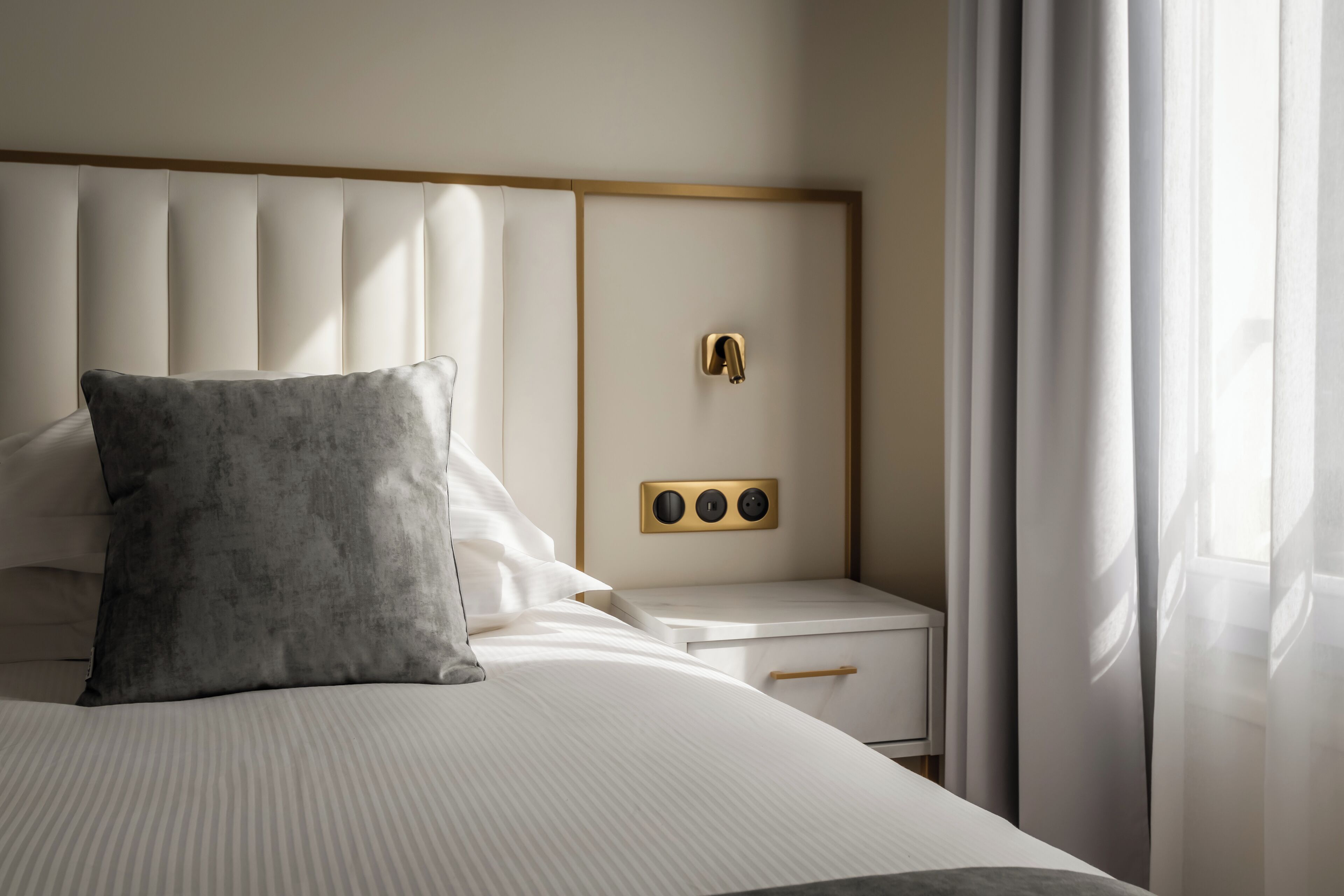 Una habitación de hotel moderna con una cama grande, una mesita de noche y una mesilla.