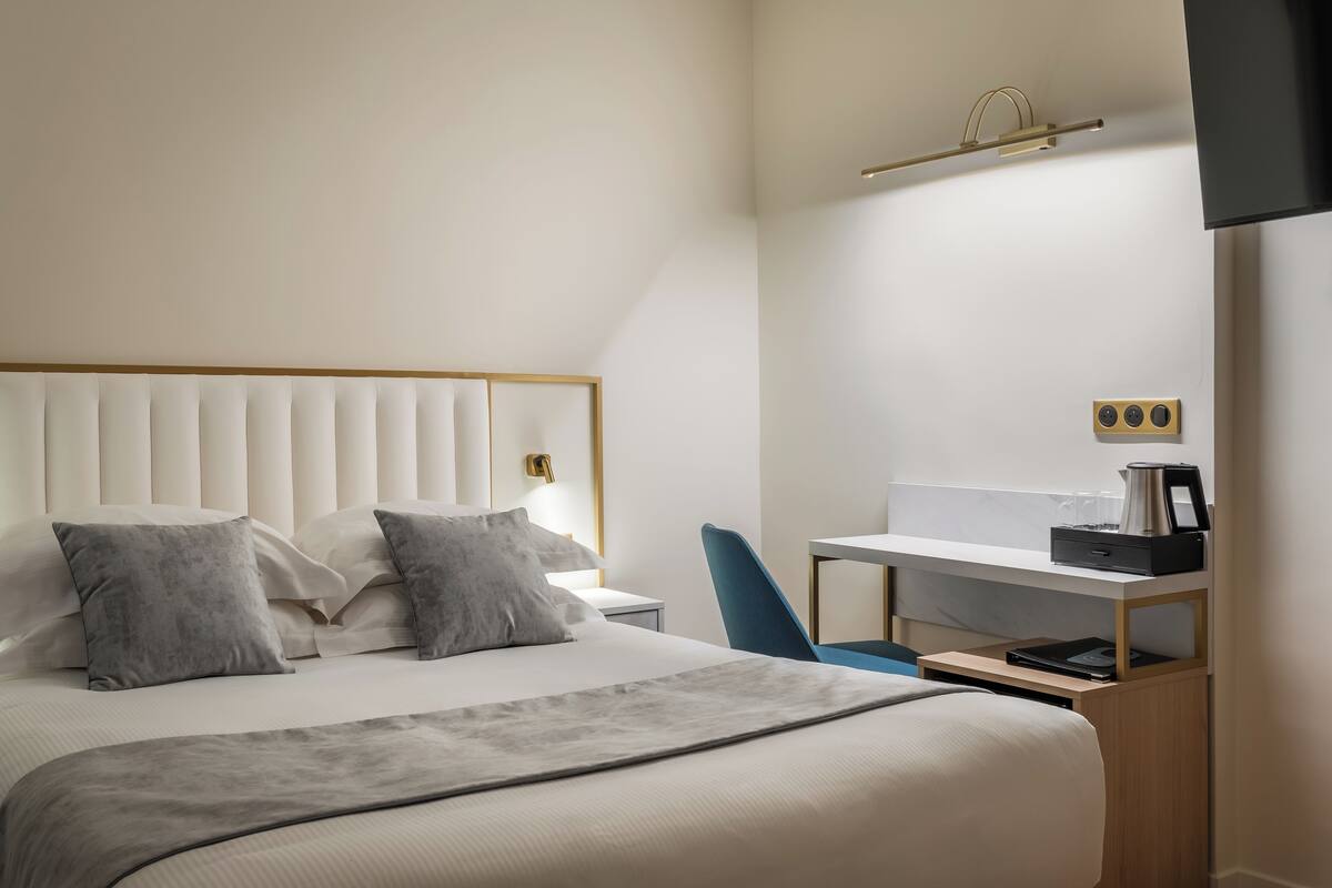 Ett modernt hotellrum med en stor säng, ett skrivbord med en dator och en platt-TV som är monterad på väggen.