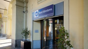 The exterior of the Best Western Crystal Palace Hotel with a glass revolving door entrance, potted plants, and a clear view of the street. - Best Western Crystal Palace Hotel (Turin)