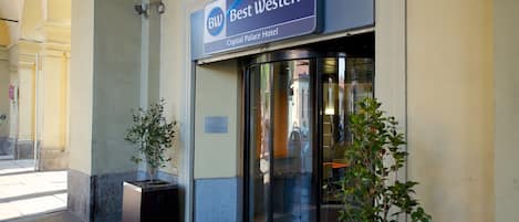 The exterior of the Best Western Crystal Palace Hotel with a glass revolving door entrance, potted plants, and a clear view of the street.