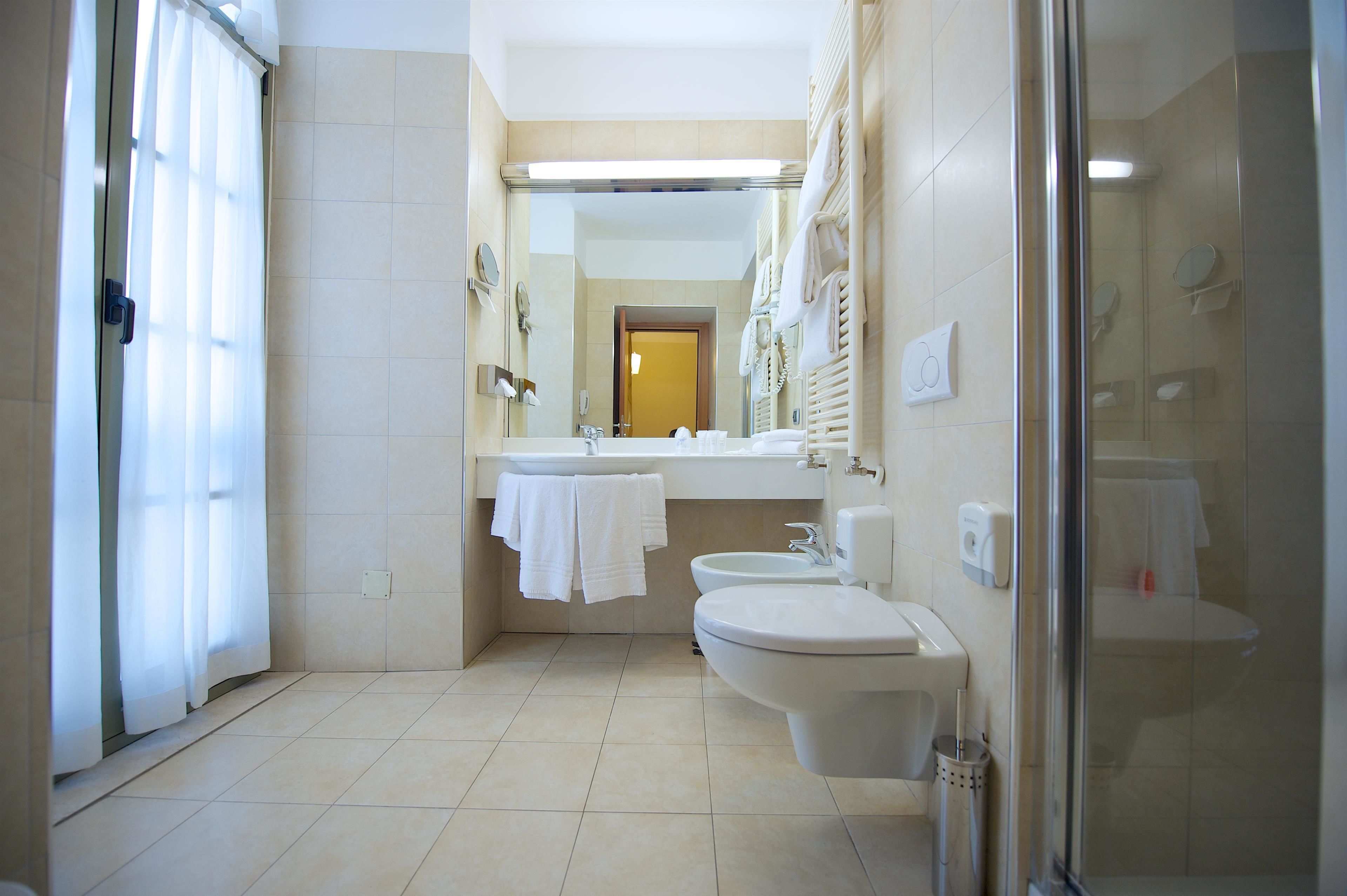 A modern bathroom with a shower, two sinks, and a toilet.