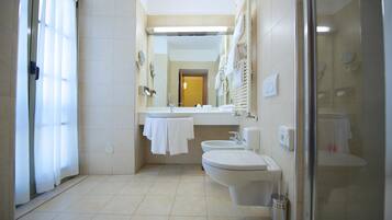 A modern bathroom with a shower, two sinks, and a toilet.