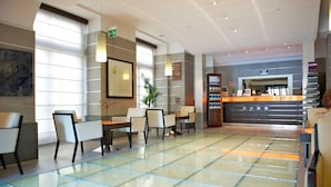 A hotel lobby with a reception desk, seating area, and a large window providing natural light. - Best Western Crystal Palace Hotel (Turin)