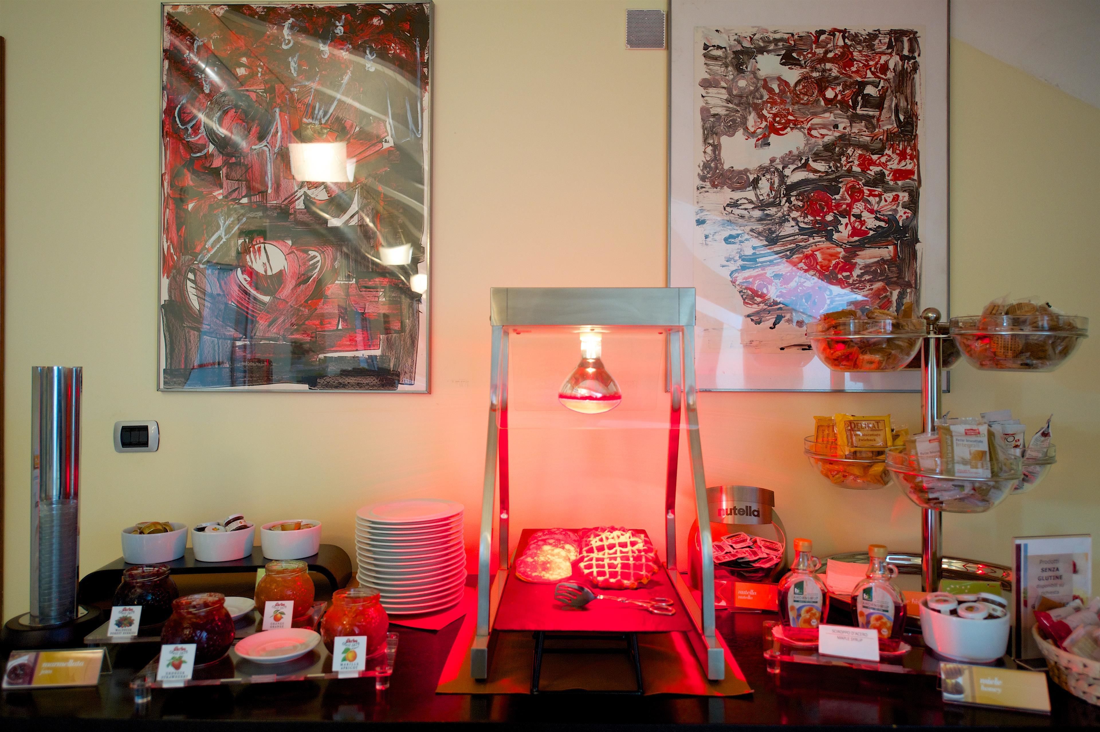 Ein reichhaltiges Buffet mit verschiedenen Speisen, einer warmhaltenden Servierstation und Kunstwerken an den Wänden.