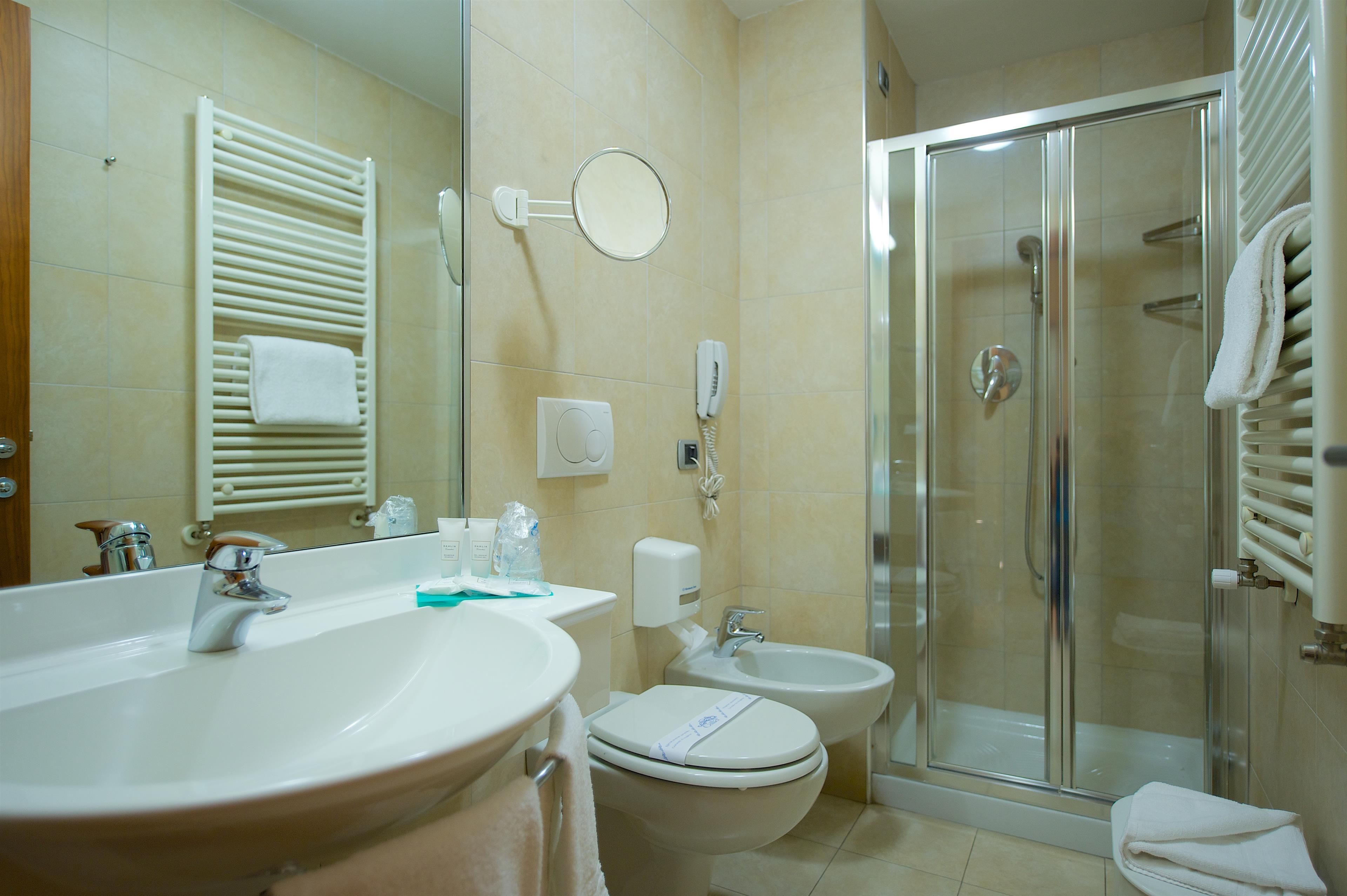 A bathroom with a sink, toilet, bidet, and glass-enclosed shower.