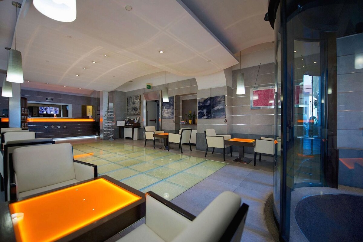 A hotel lobby with a reception desk, seating area, and a glass partition.
