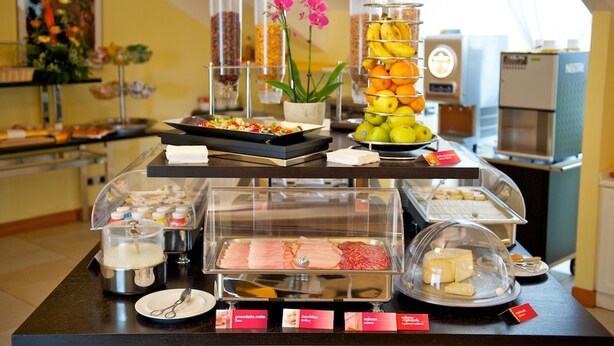 A buffet setup with various food items, including fruits, meats, and cheeses, displayed in clear containers. - Best Western Crystal Palace Hotel (Turin)