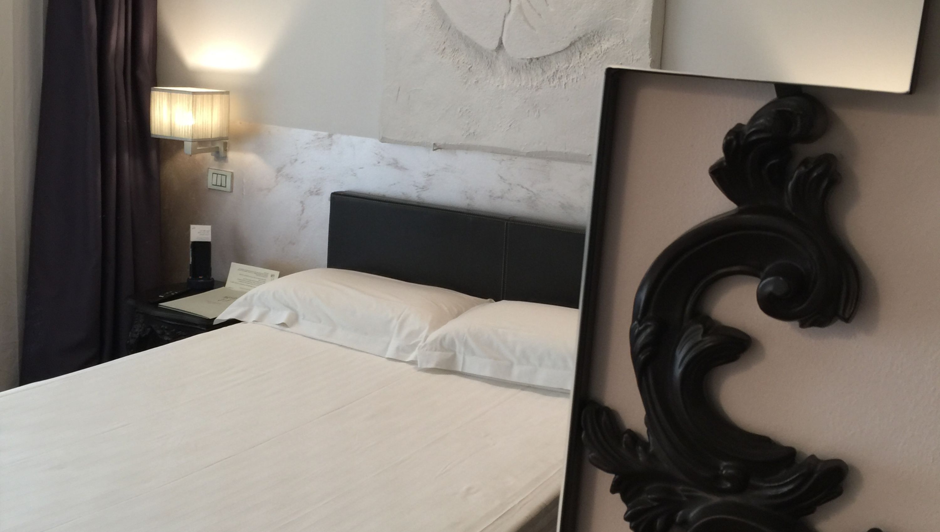 Habitación de hotel con cama, mesita de noche, lámpara y un adorno en la pared.