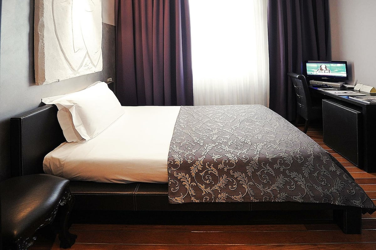 Een hotelkamer met een bed, een bureau en een televisie.