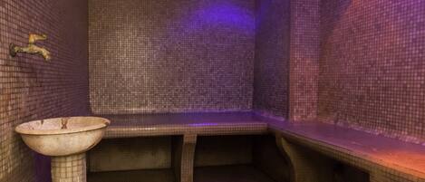 A small, tiled room with a bench and a sink.