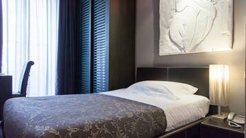 Ein Hotelzimmer mit Bett, Nachttischlampe, Telefon und einem großen Wandbild.