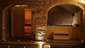 A stone-walled sauna with wooden benches and a bench with a towel.