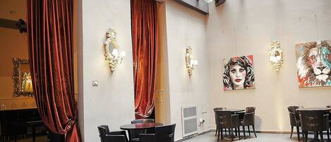 En rummelig galleri med højt til loftet, store vinduer og røde gardiner.