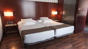 A double bed room with two bedside tables, each with a lamp, and a wooden floor.