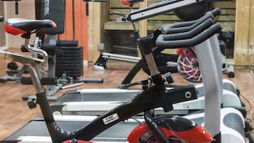 Un gimnàs amb bicicletes estàtiques, màquines de peses i un mirall gran.