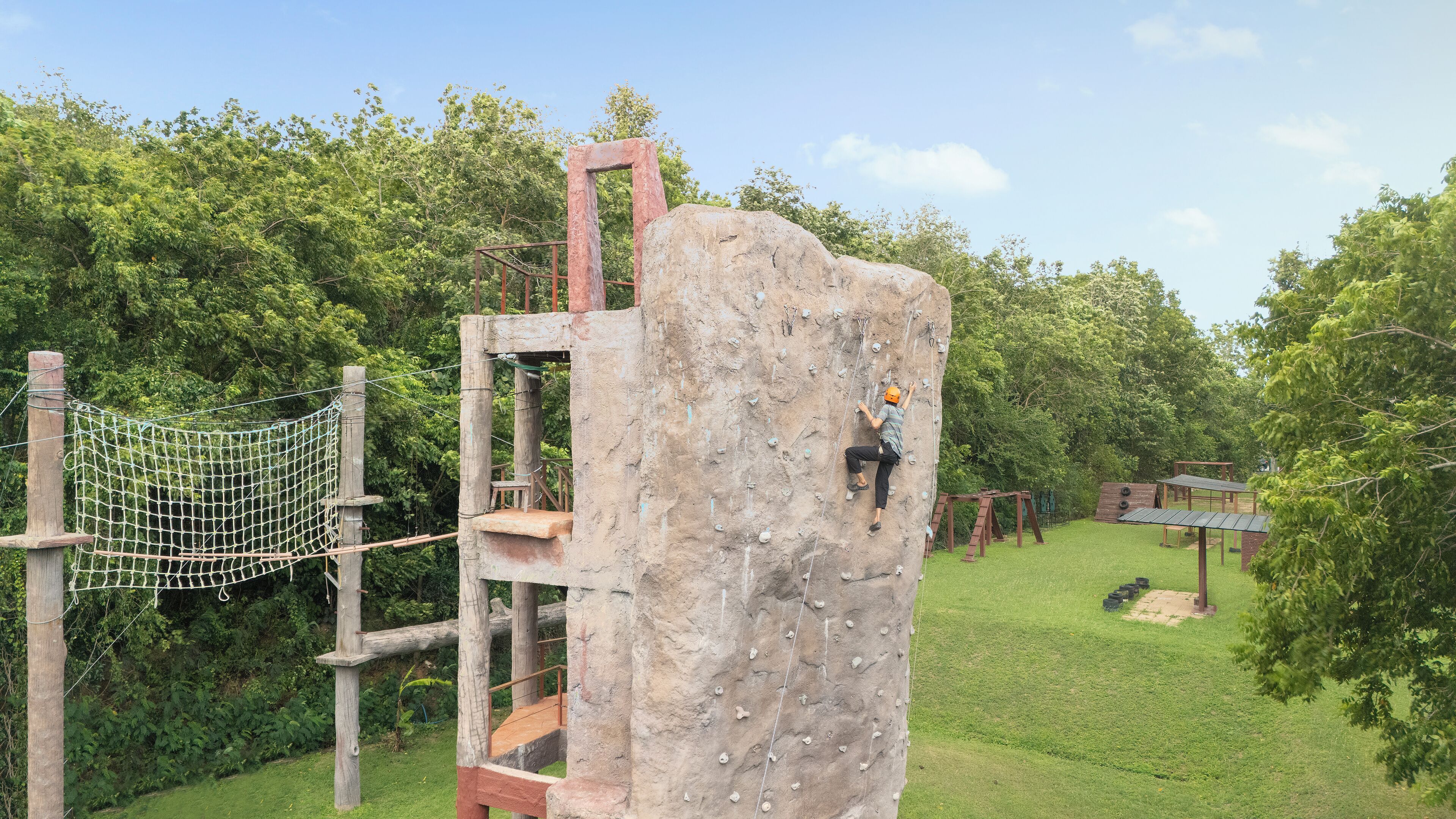 Un mur d’escalade avec une échelle en bois et un filet de sécurité.