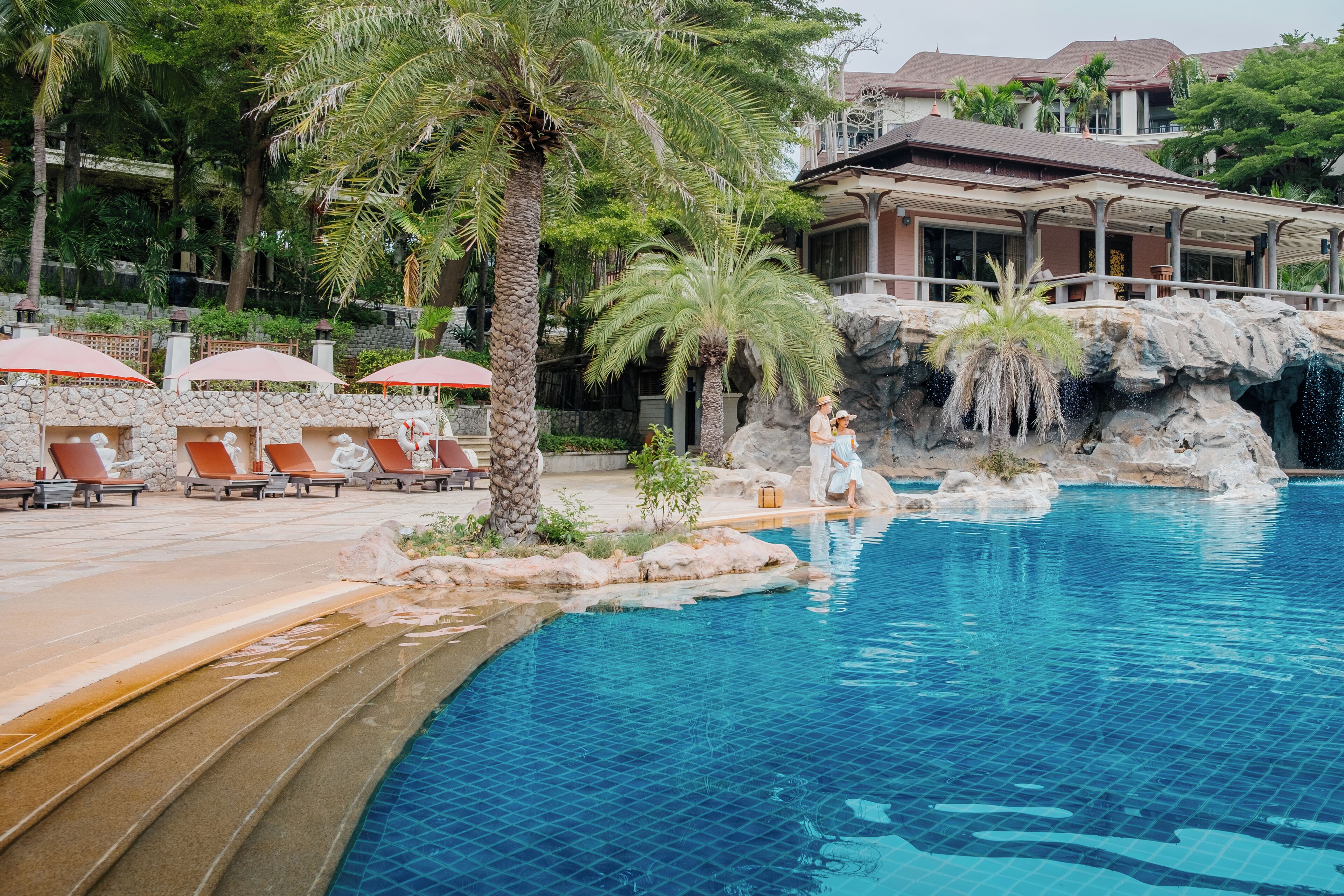 Un área de piscina con sillones de descanso y una cascada.