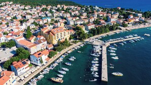 An aerial view of a coastal town with a marina filled with boats, surrounded by residential buildings with red-tiled roofs. - Hotel Selce  (Crikvenica)