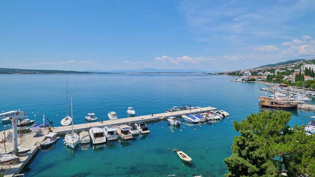 A marina with boats docked, a pier, and a view of a coastal town. - Hotel Selce  (Crikvenica)