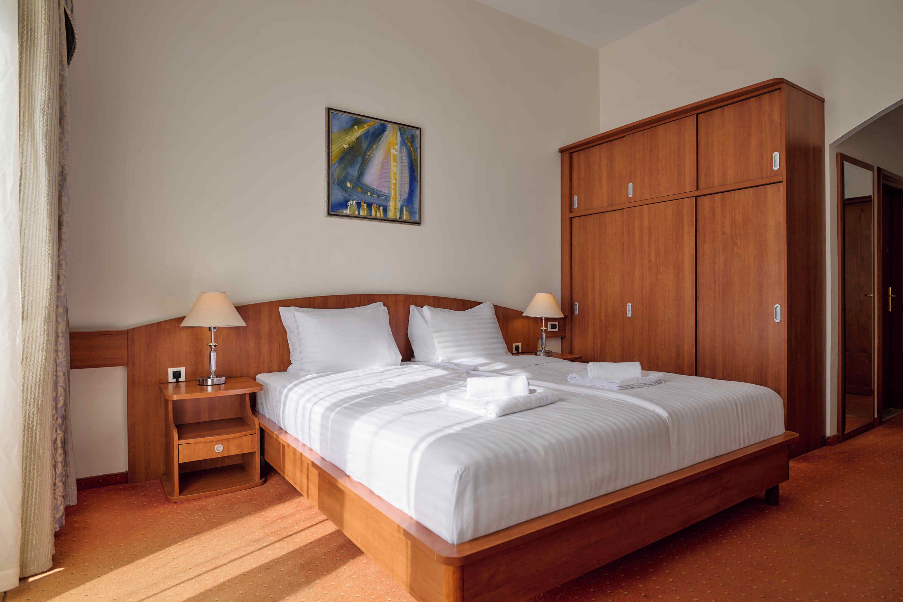 Ein Hotelzimmer mit einem großen Bett, einem Holzschrank und einem Bild an der Wand.