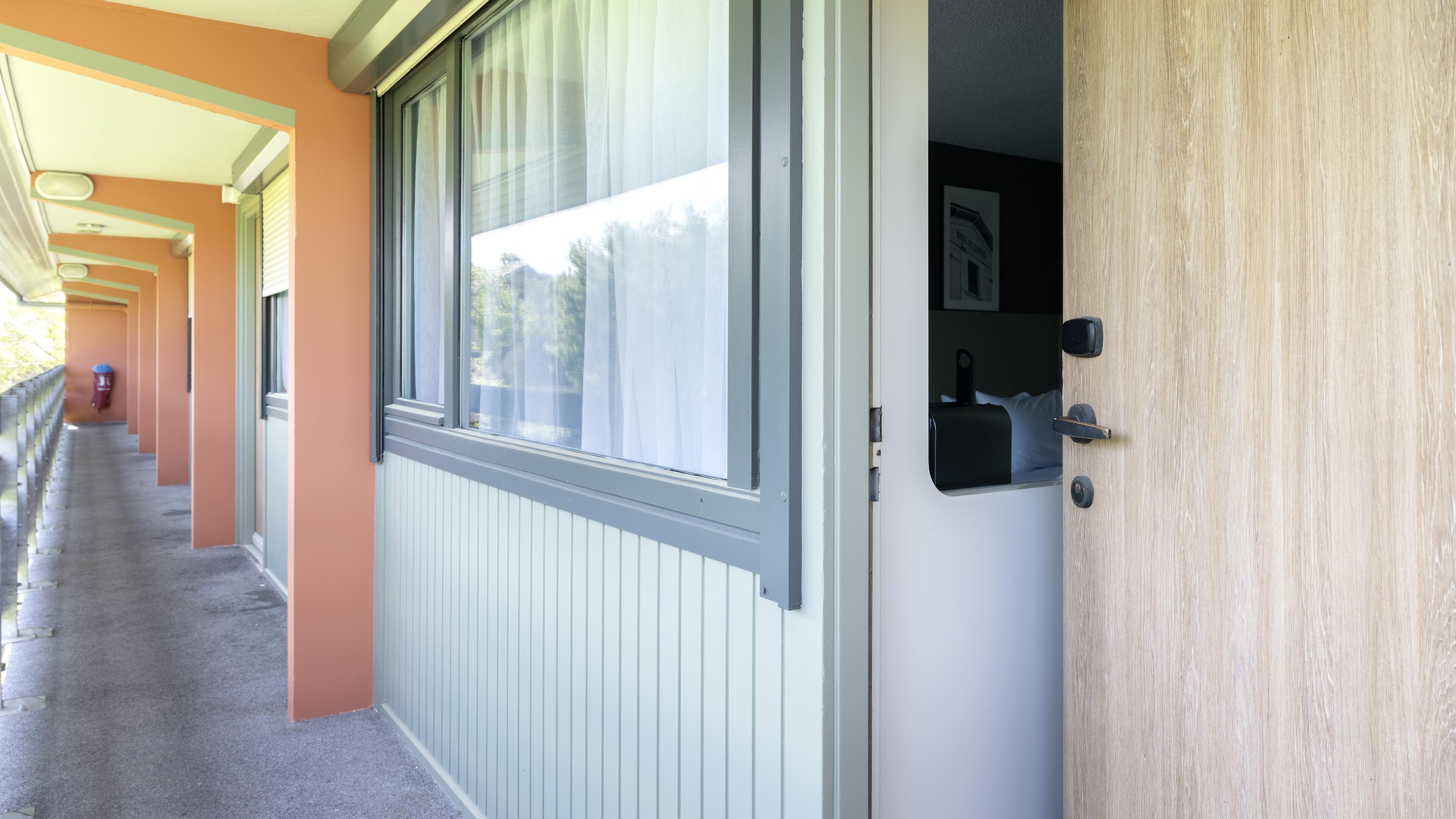 Ein Flur mit einer Tür zu einem Zimmer, das ein Fenster und einen Briefkasten hat.