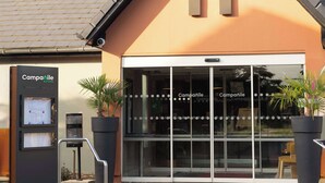 A building with a modern design, featuring a prominent 'A' logo on the facade, a water dispenser, and potted plants. - Campanile NATURE - Mont de Marsan (Mont-de-Marsan)