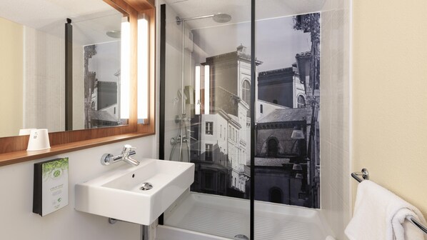 Un baño con un lavamanos blanco, un espejo y una ducha.