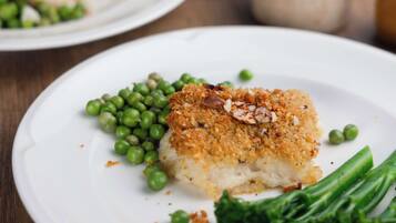 A dining table with plates of food, including a breaded item and green vegetables.