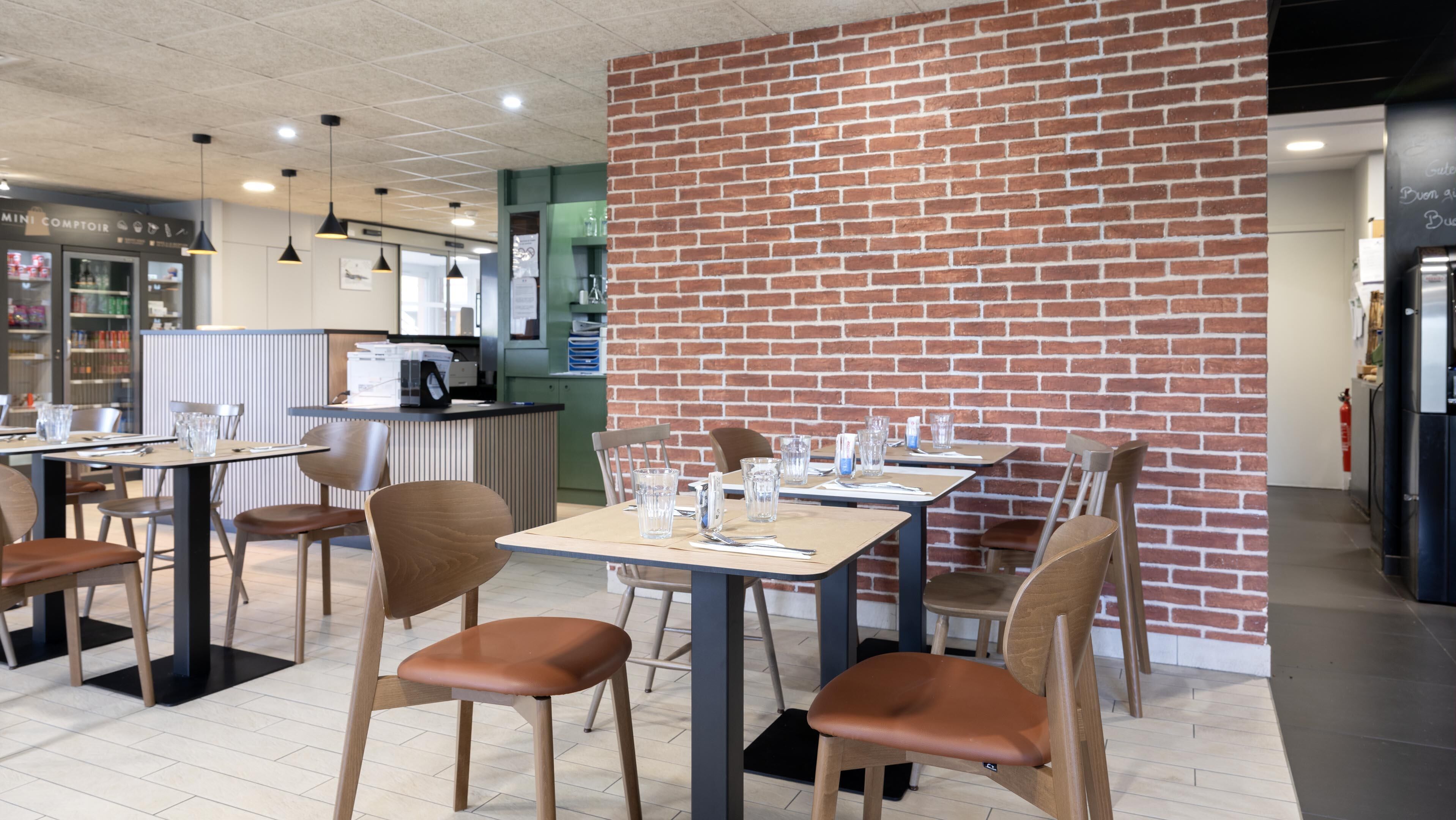 Un restaurante con paredes de ladrillo, mesas y sillas de madera.