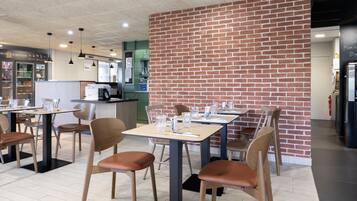 Un restaurante con paredes de ladrillo, mesas y sillas de madera.