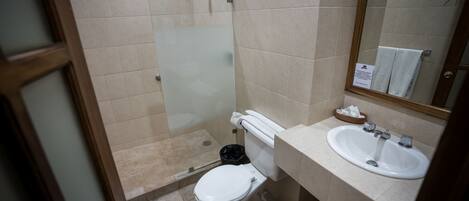 Un baño con inodoro, lavamanos y cabina de ducha de vidrio.