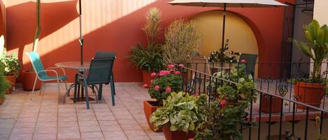 An outdoor patio with tiled flooring, potted plants, and outdoor furniture.