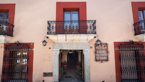 Ein Gebäude mit roter und beiger Fassade, einem Balkon mit schmiedeeisernen Geländern und einem Schild, das es als Hotel, Restaurant und Bar kennzeichnet.