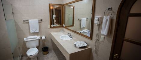 A bathroom with a toilet, sink, and mirrors.