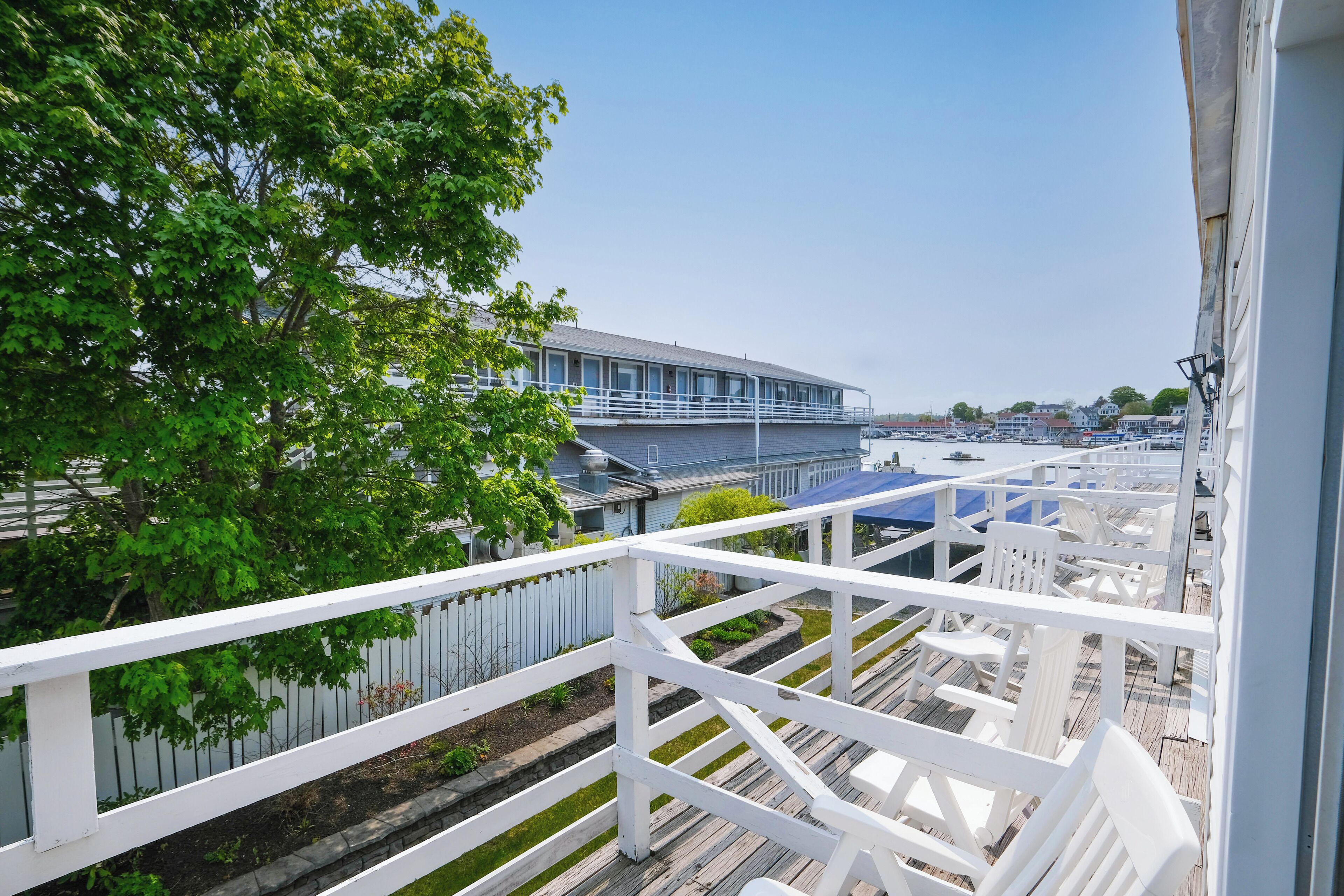 A balcony with white railings overlooking a marina with boats and a building in the background.