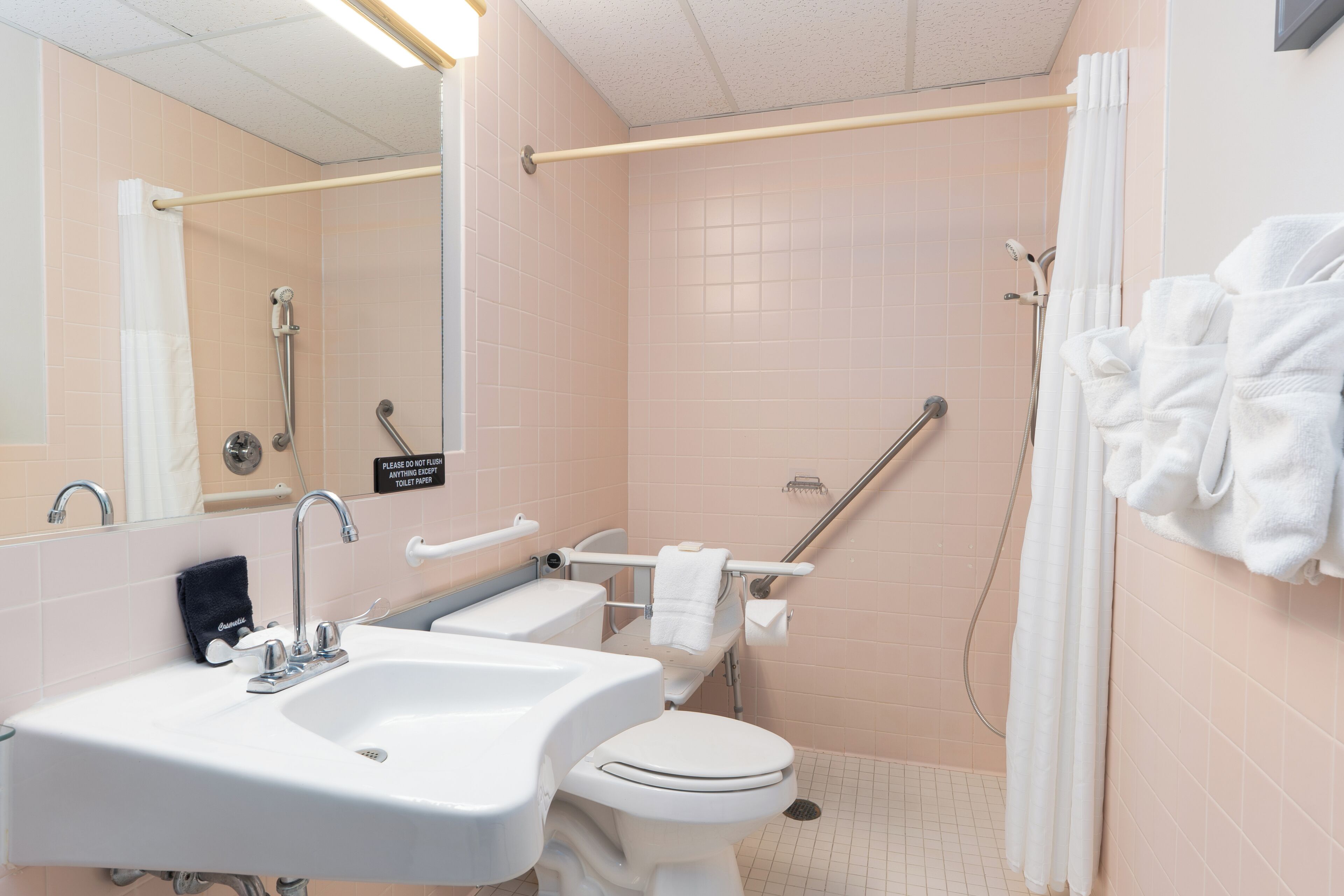 A bathroom with two sinks, a toilet, a shower with a grab bar, and a towel rack.