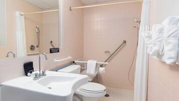 A bathroom with two sinks, a toilet, a shower with a grab bar, and a towel rack.